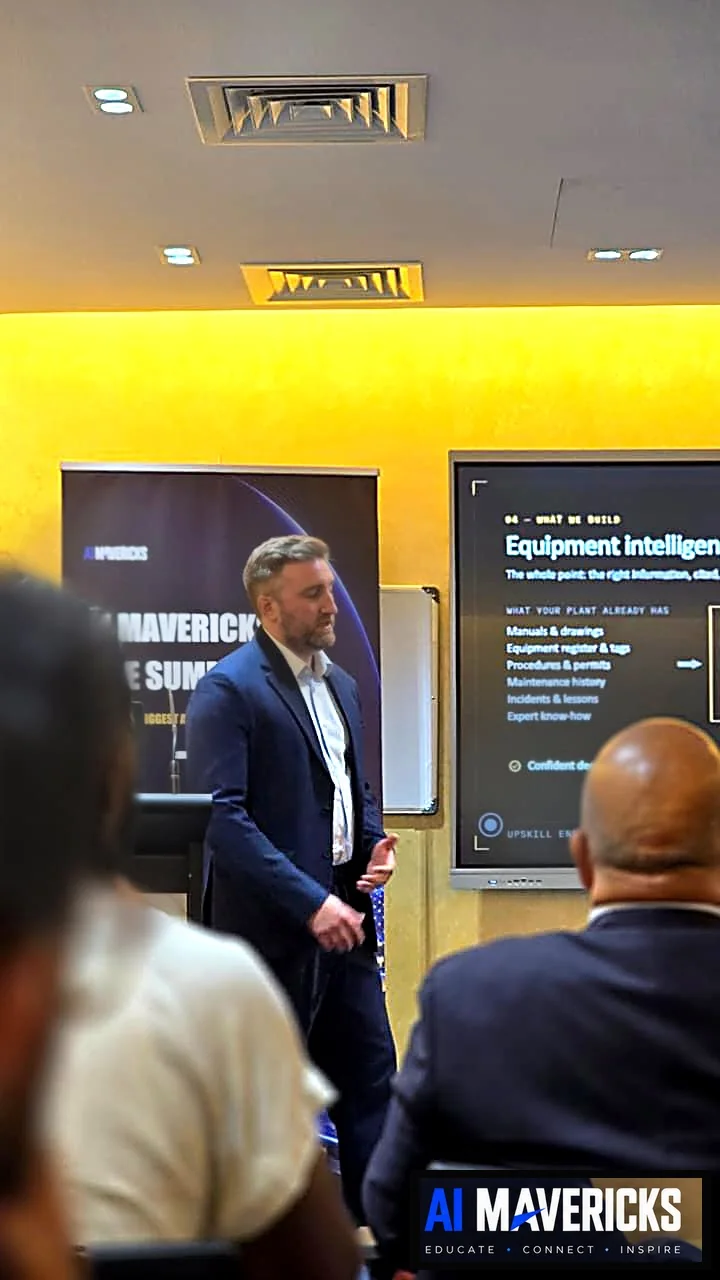 A speaker in a navy blazer presenting to the AI Mavericks audience